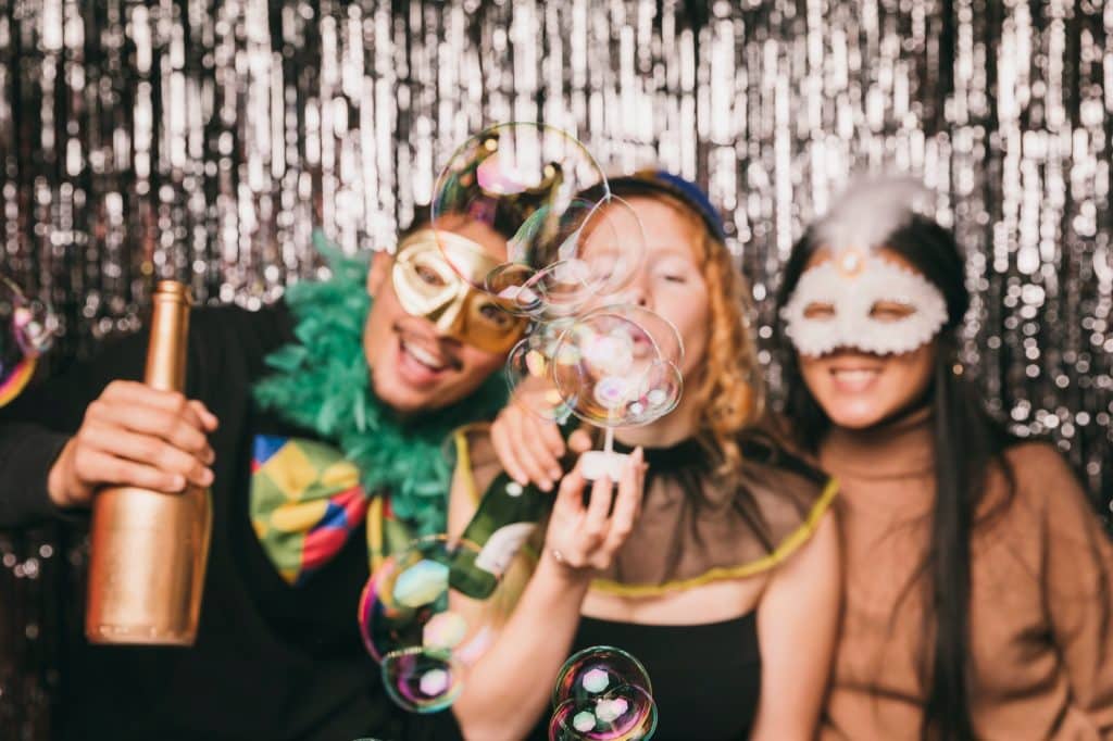 Friends in masks and party props in a photobooth