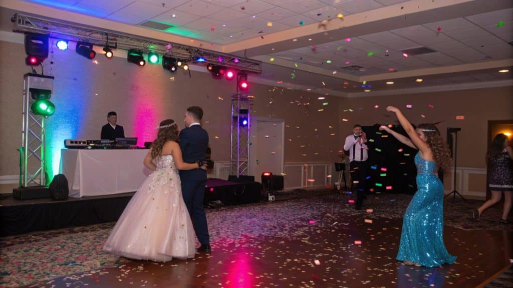 Students dancing under DJ lights at a high school prom